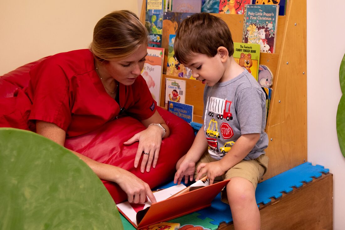 A teacher with a male child reading a book